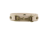Beige leather bracelet with brass horse bit design on a white background